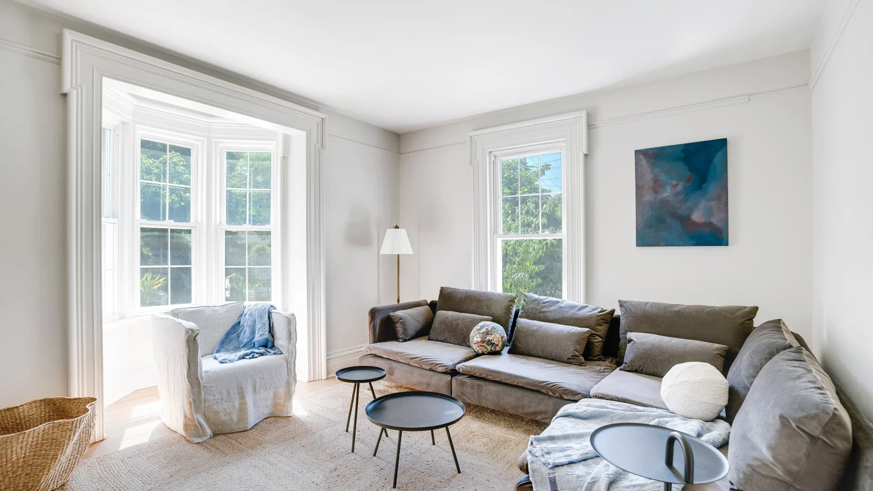 A bright living room with a sectional sofa and several large windows.