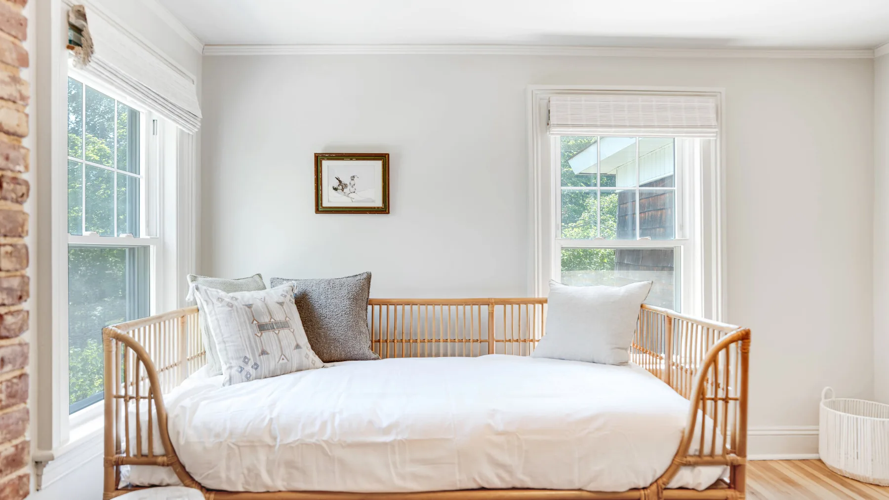 A bright bedroom with a daybed beneath two windows.
