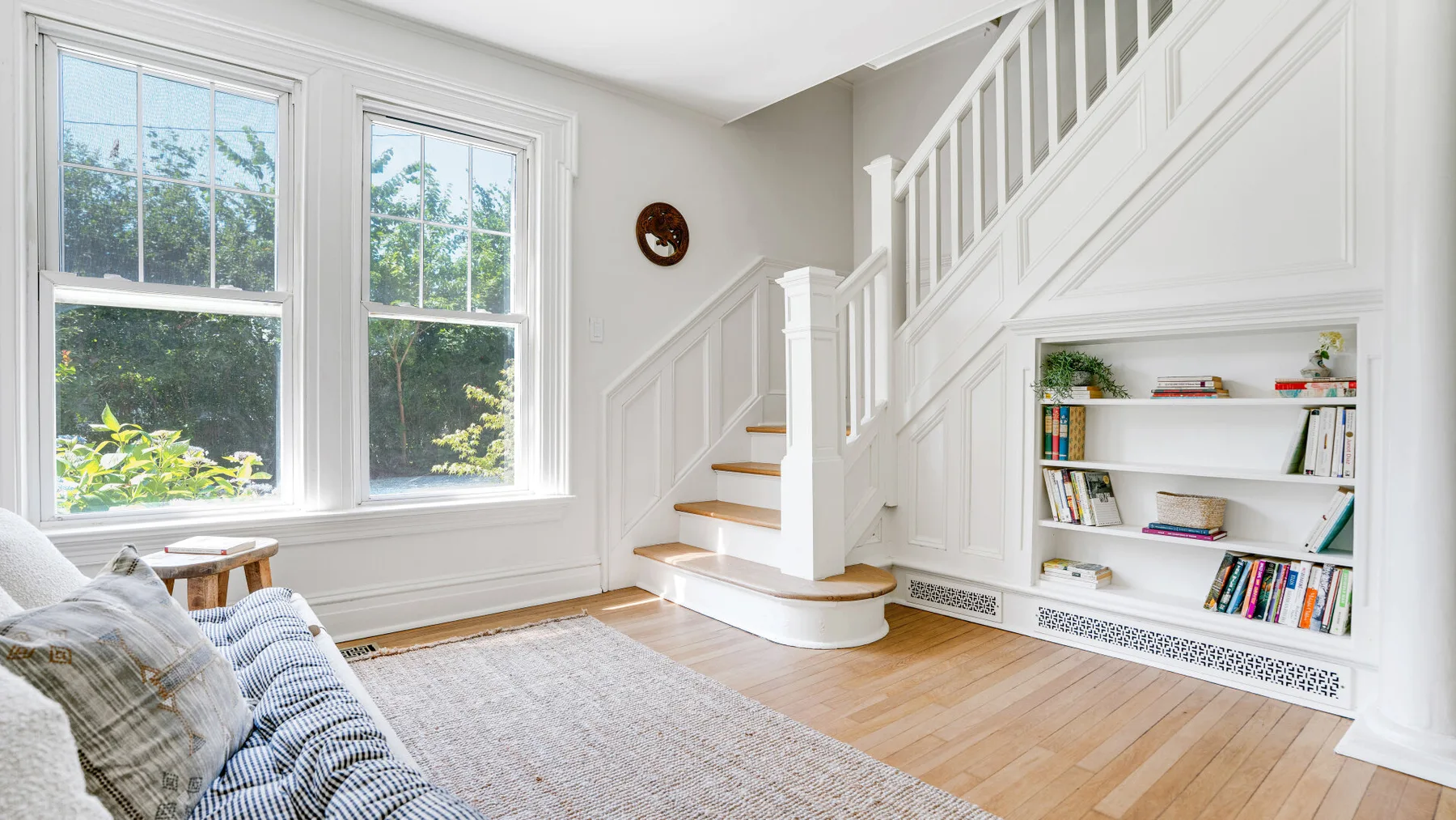 A bright living area with large windows, a staircase, and built-in shelving.