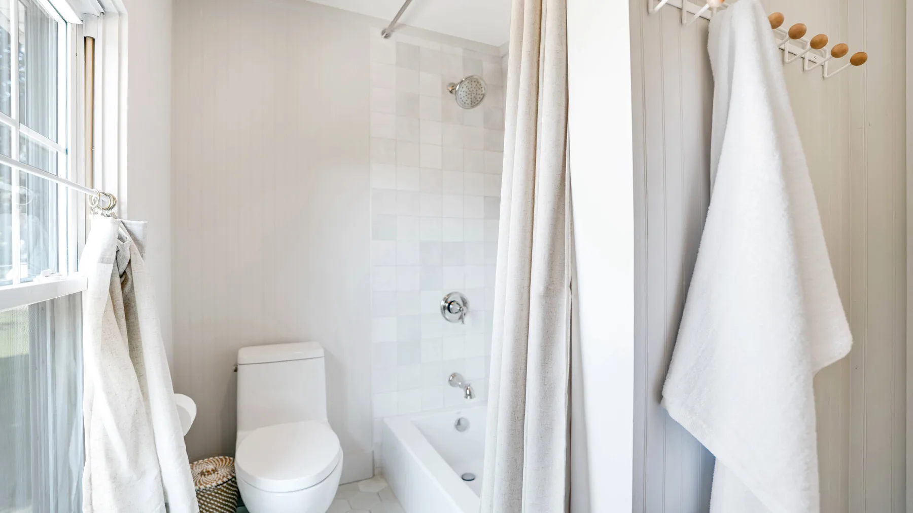 A bright bathroom with a bathtub, shower, and white towels.