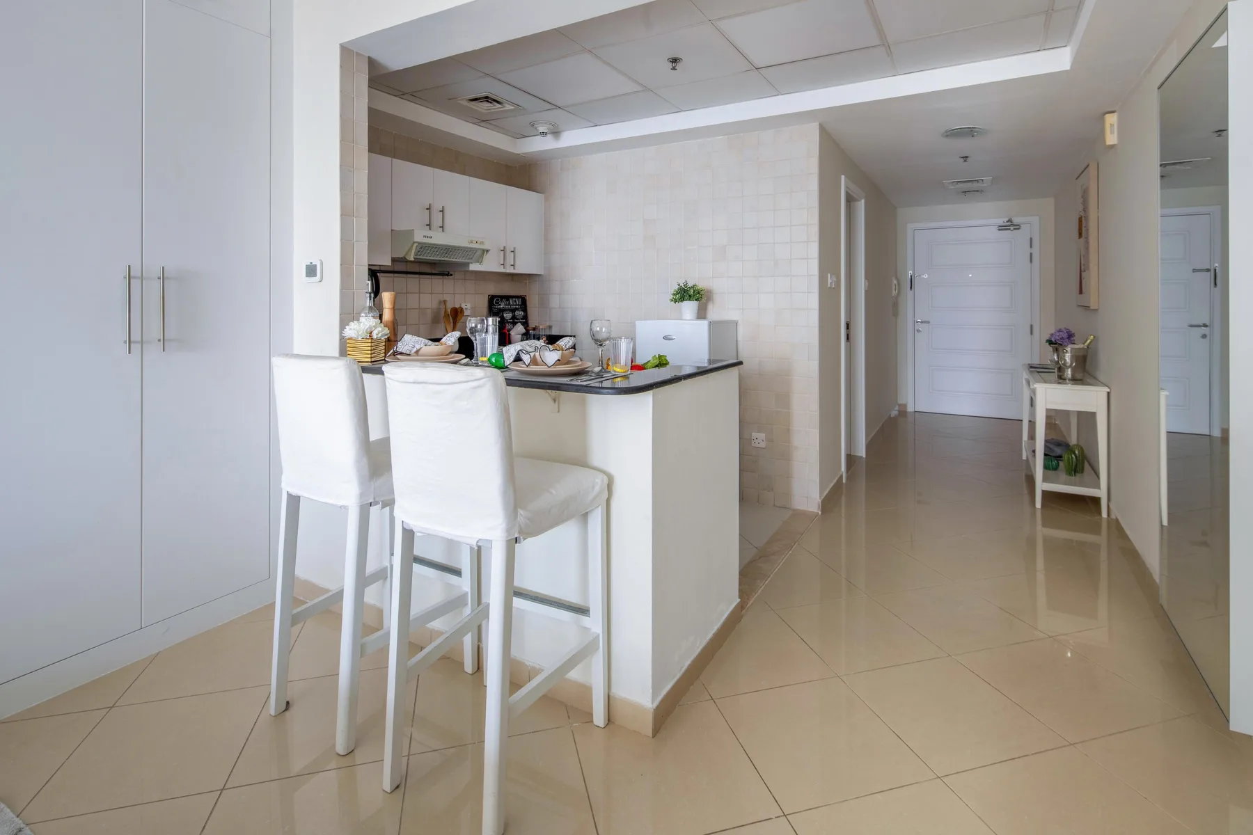 Una cocina luminosa da a un pasillo, con una encimera y asientos.