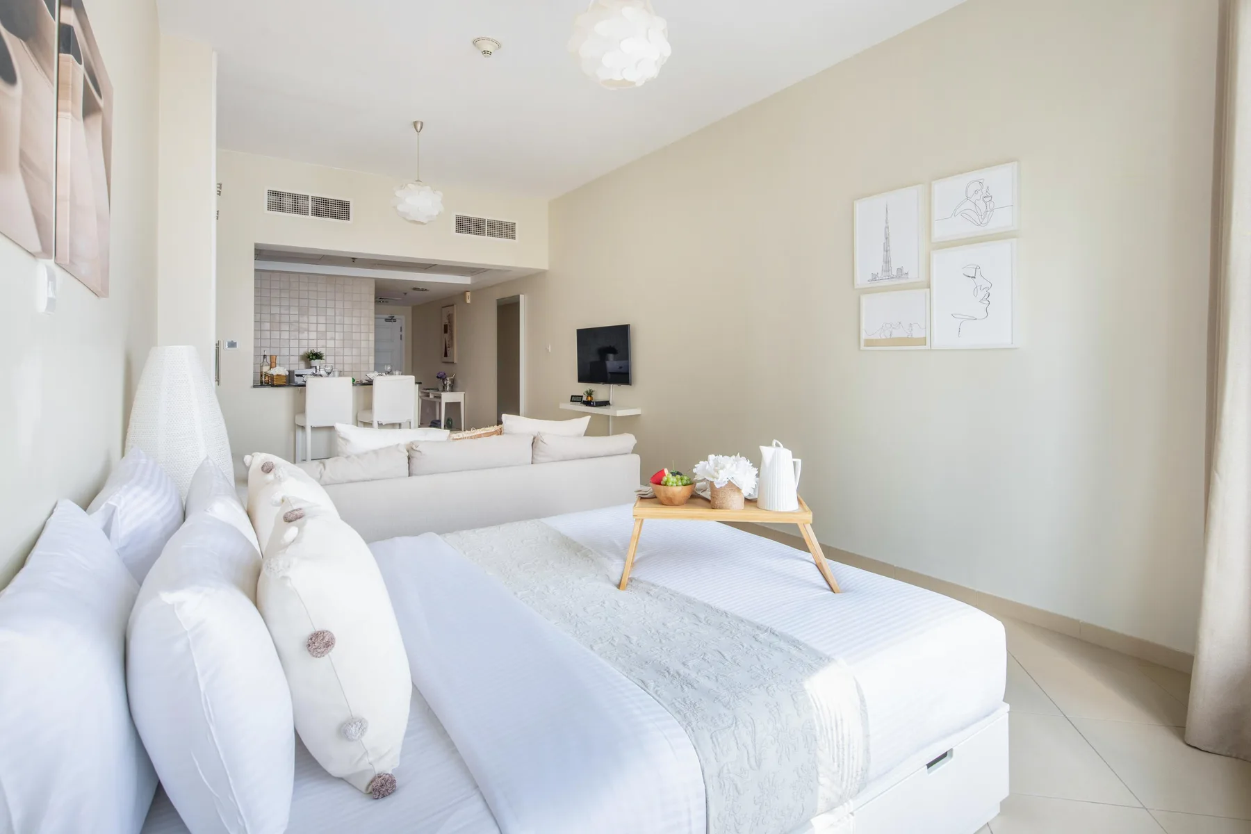 Un dormitorio luminoso con ropa de cama blanca y una mesita junto a la cama.
