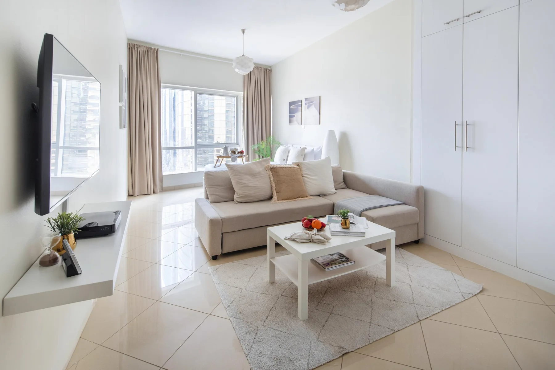 Una sala luminosa con sofá seccional, mesa de centro y ventanas grandes.