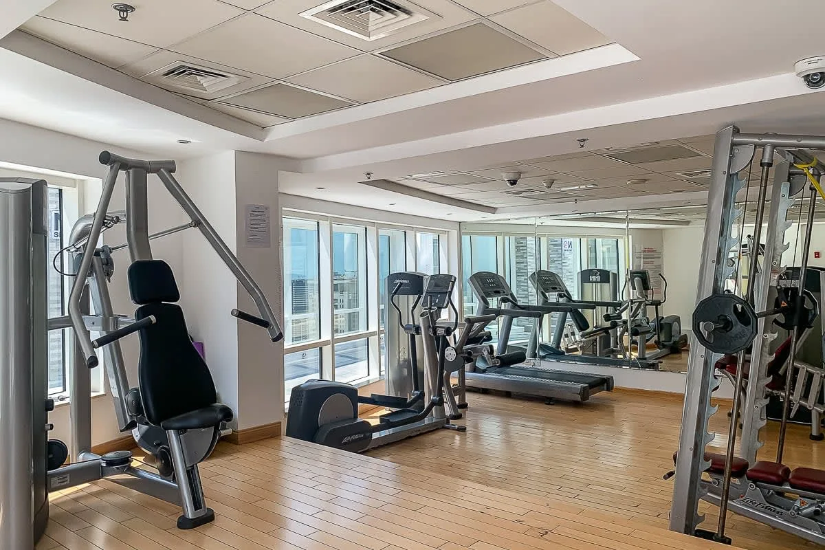 Un gimnasio con equipos de ejercicio frente a paredes con espejos.