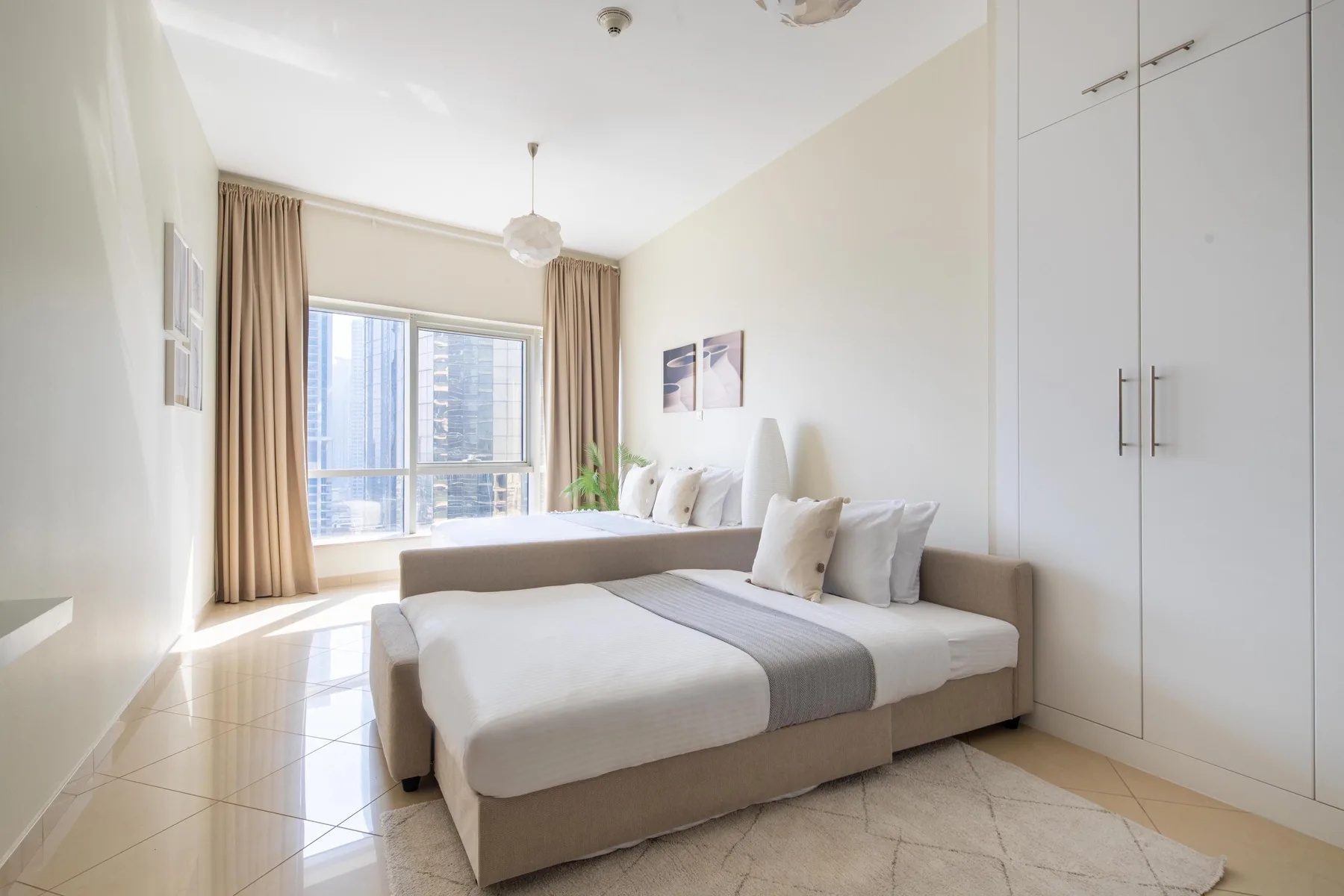 Un dormitorio luminoso con una cama junto a una ventana grande y armarios empotrados.