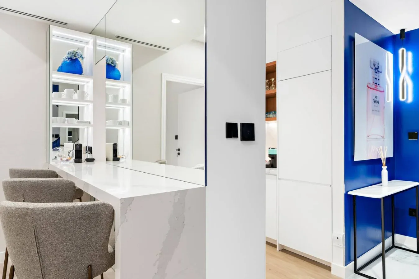 Un tocador de baño luminoso con un espejo amplio y asientos tapizados en gris.