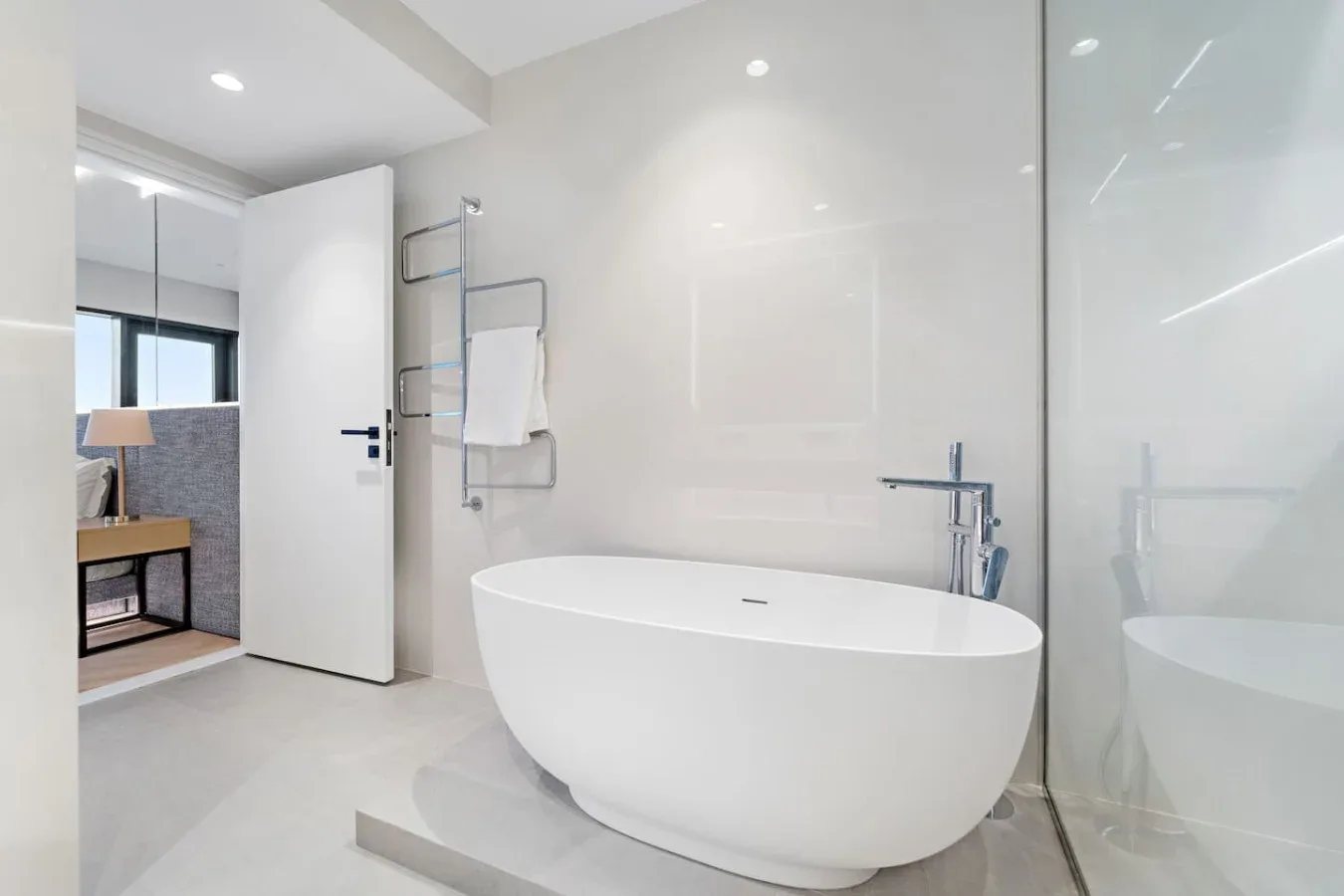 Un baño luminoso con una bañera exenta junto a una ducha de vidrio.