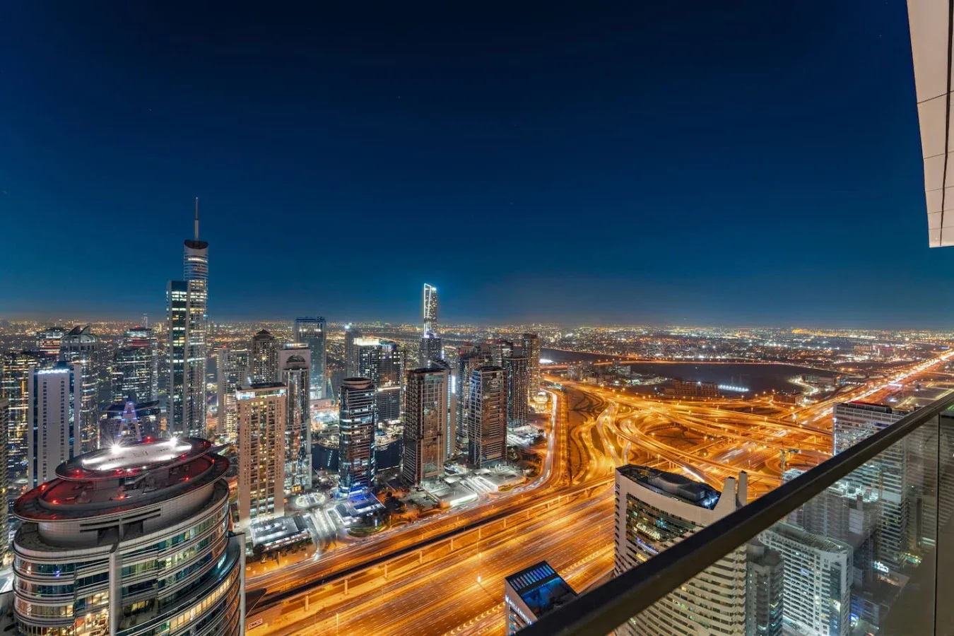 Horizonte urbano nocturno con autopistas iluminadas y edificios altos.