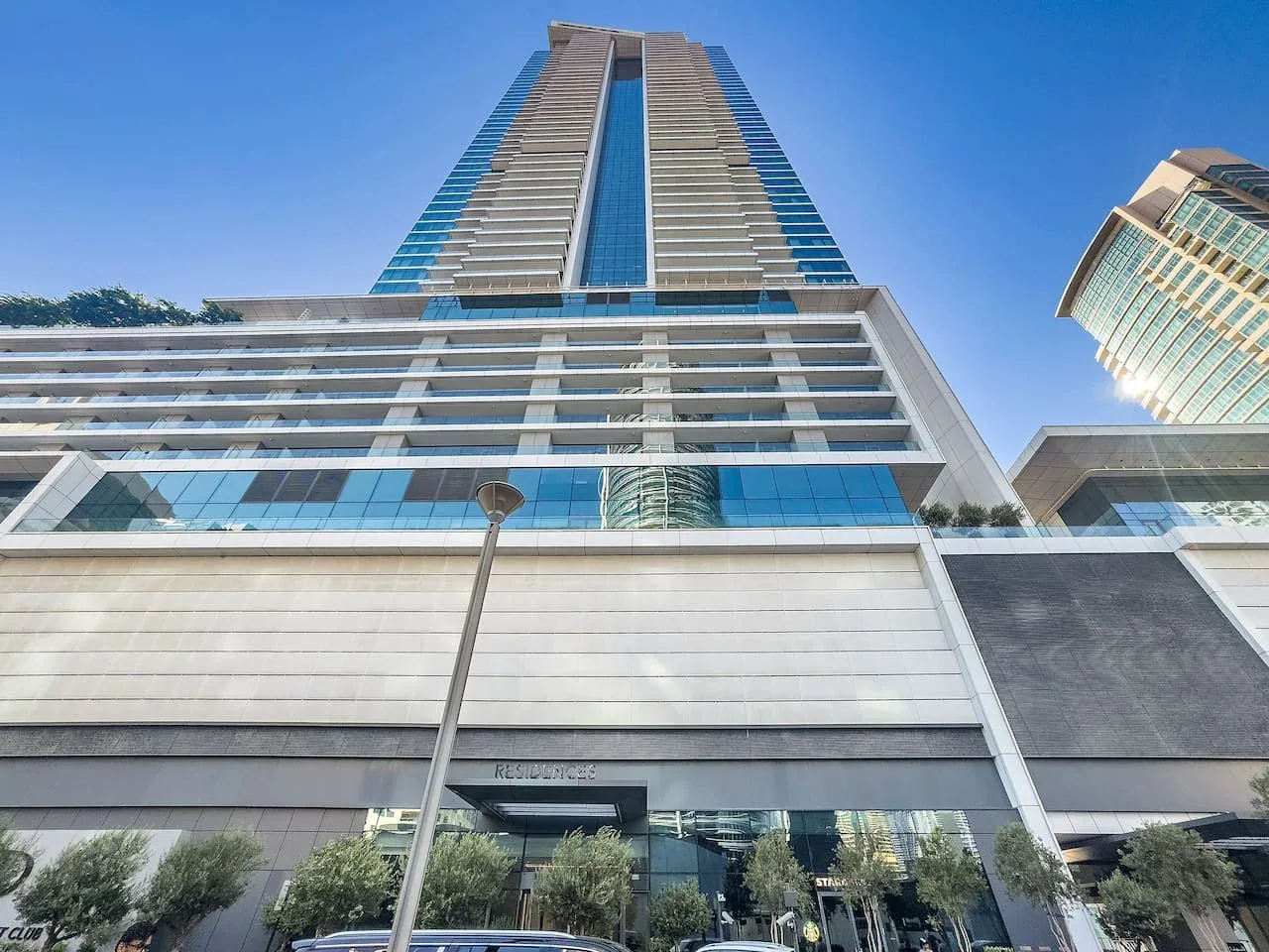 Un edificio moderno de gran altura visto desde abajo bajo un cielo azul despejado.