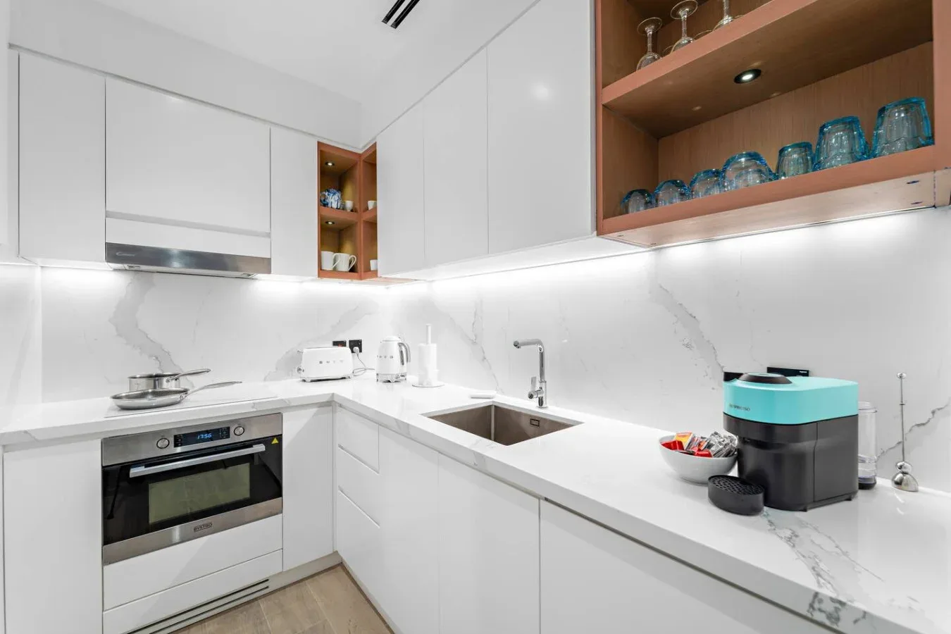Una cocina blanca moderna con horno, fregadero y estantes abiertos.