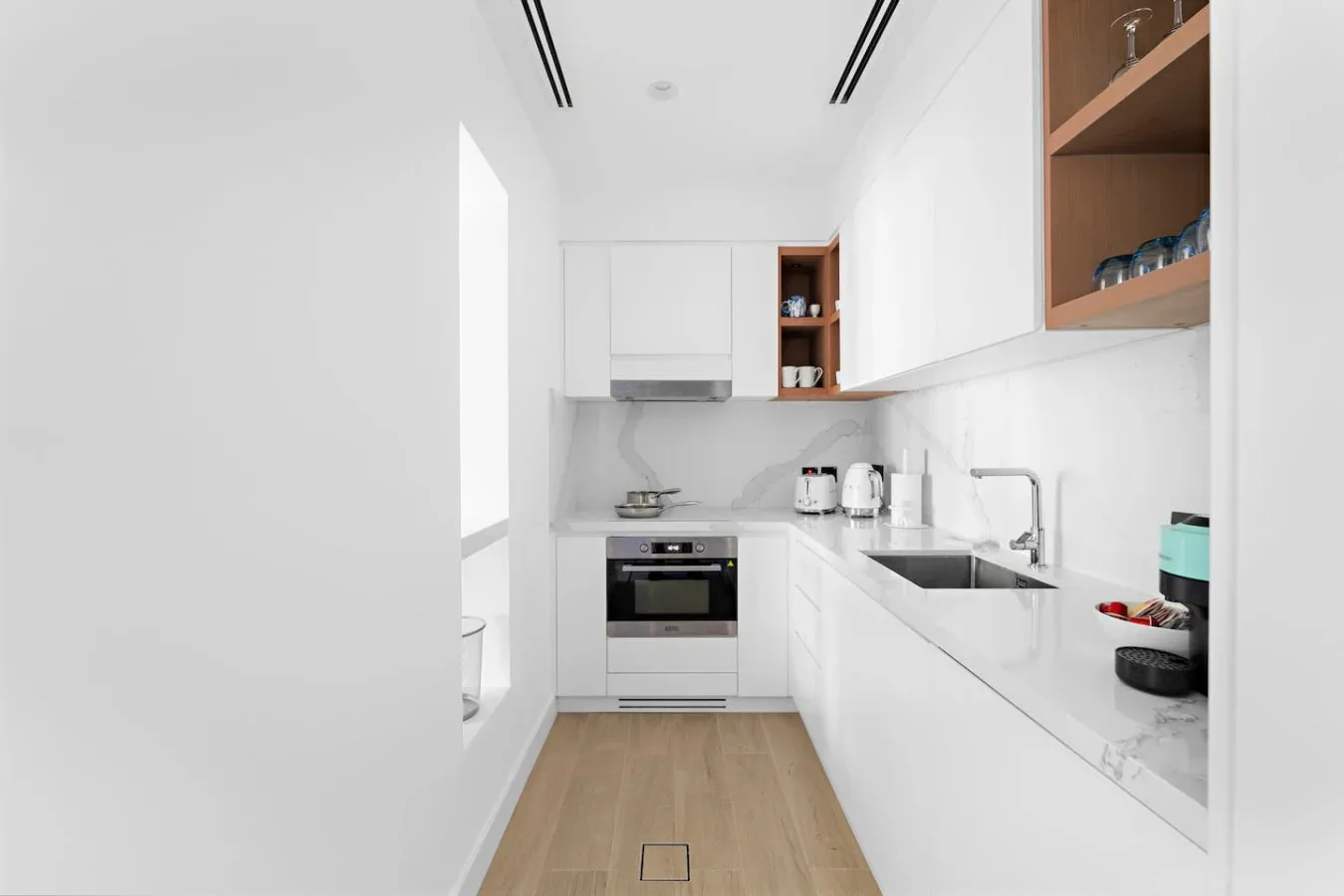 Una cocina luminosa y moderna con gabinetes blancos y una encimera larga.