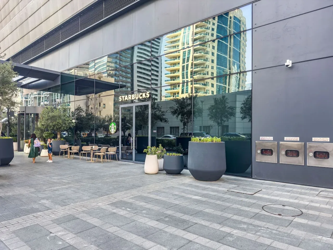 La entrada de un café Starbucks da a una plaza pavimentada con asientos al aire libre.