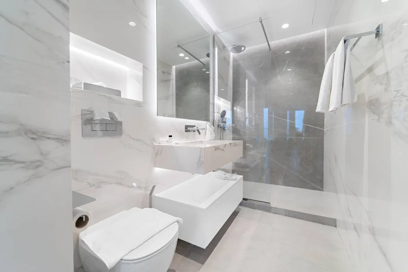 Un baño luminoso con lavabo, inodoro y ducha de vidrio.