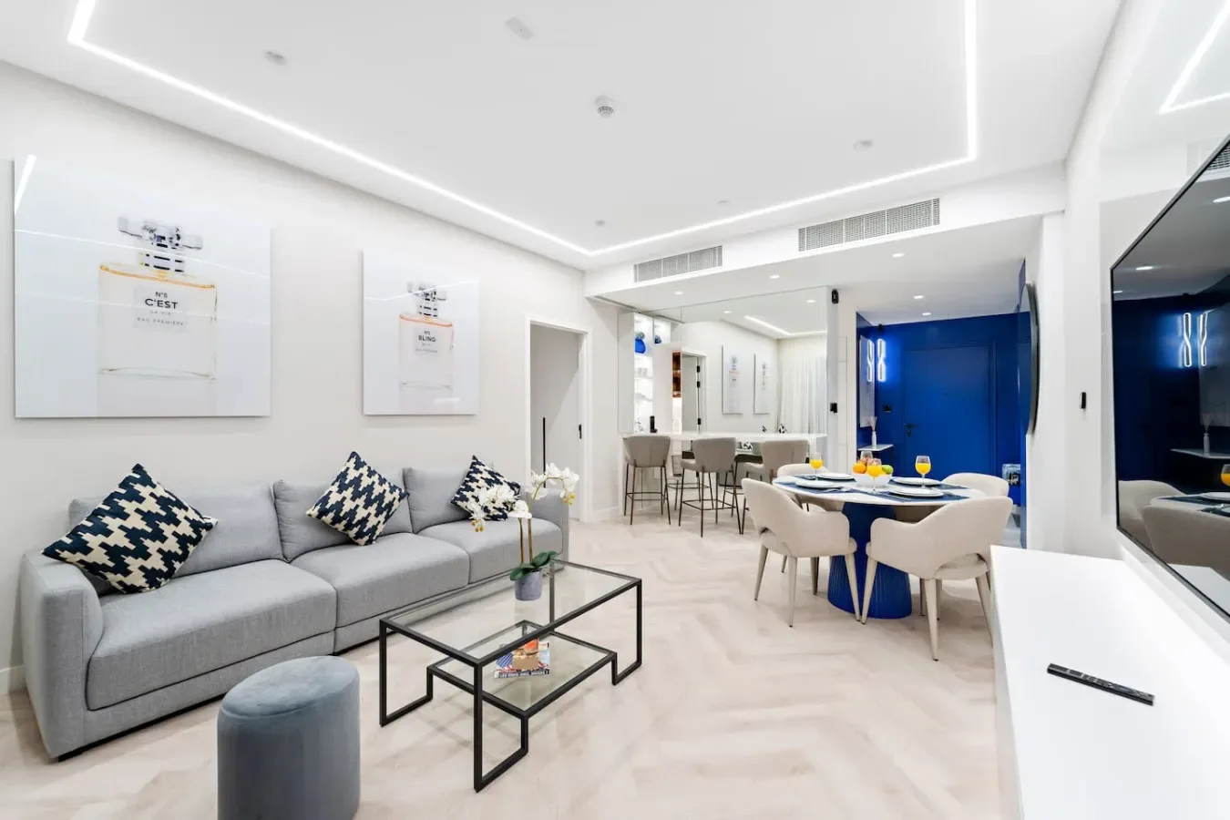 Una luminosa sala de estar y comedor de concepto abierto con un sofá gris y una mesa de comedor.