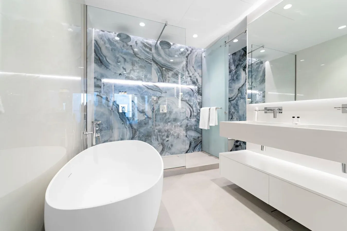 Un baño luminoso con bañera exenta, ducha de vidrio y un largo lavabo.