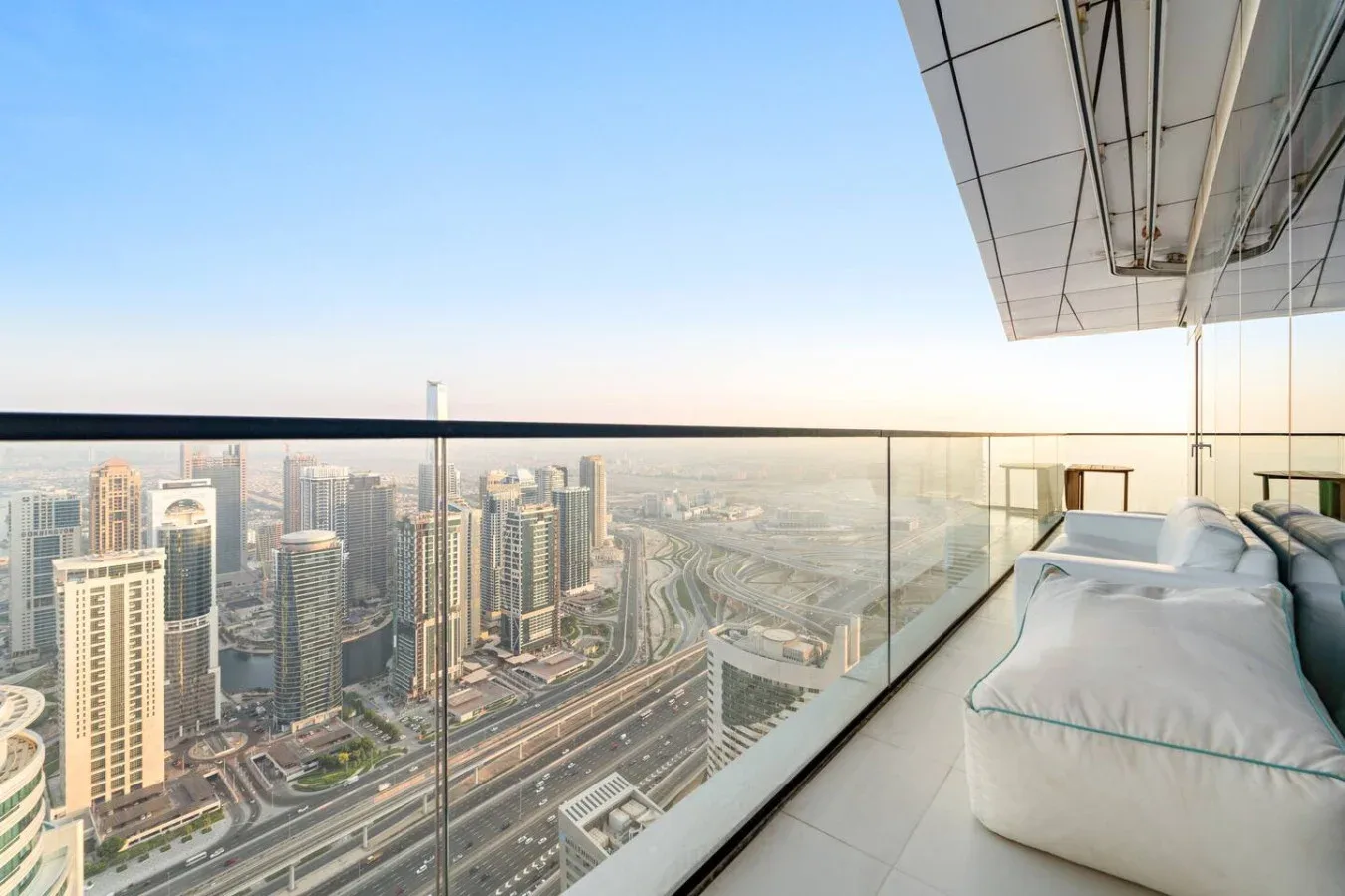 Una zona de estar en el balcón da a un horizonte urbano y vías elevadas.
