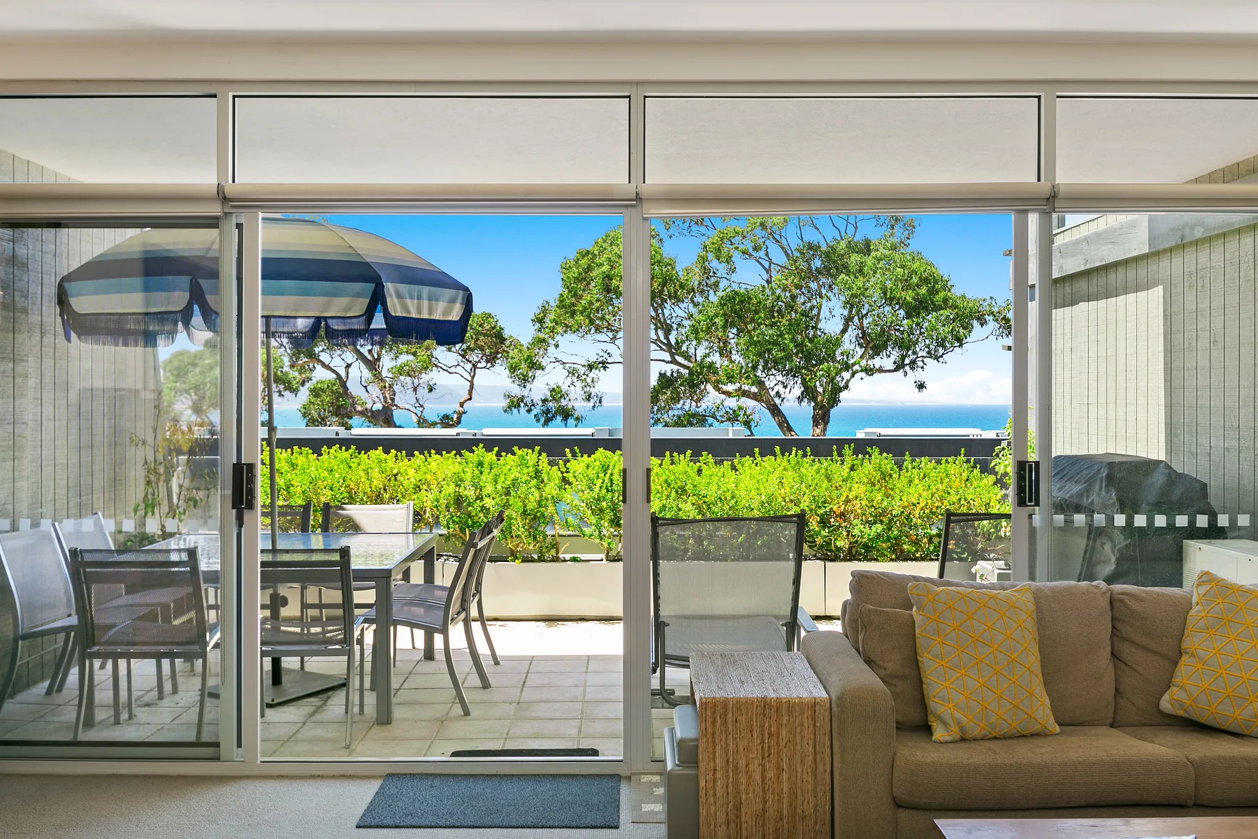 Sala de estar con puertas corredizas de vidrio que dan a un patio y vistas al mar.