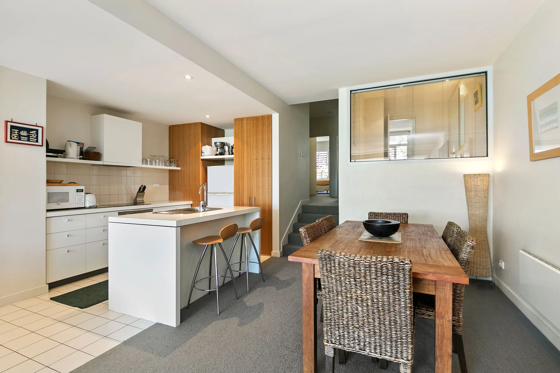 Una cocina y comedor de planta abierta con una isla central y una mesa de madera.
