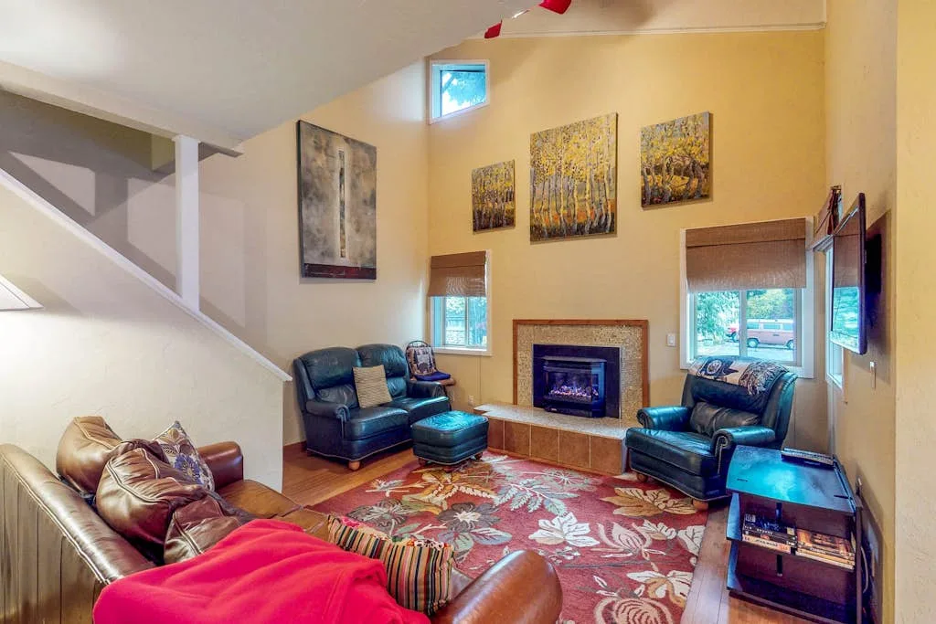 A living room with seating arranged around a fireplace and a patterned rug.