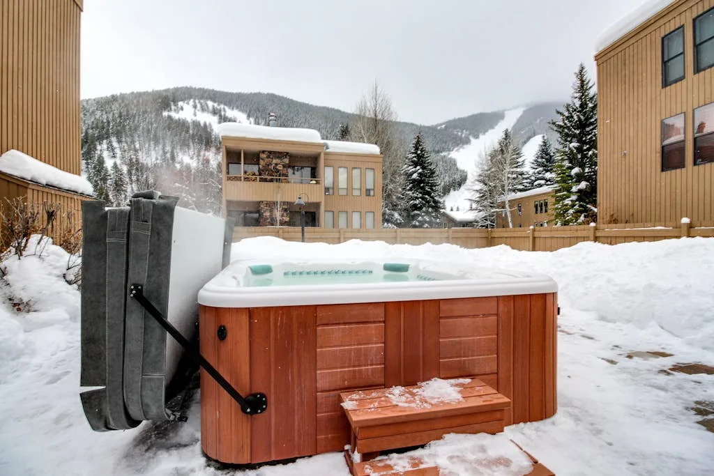 A hot tub sits in a snowy outdoor courtyard between buildings.
