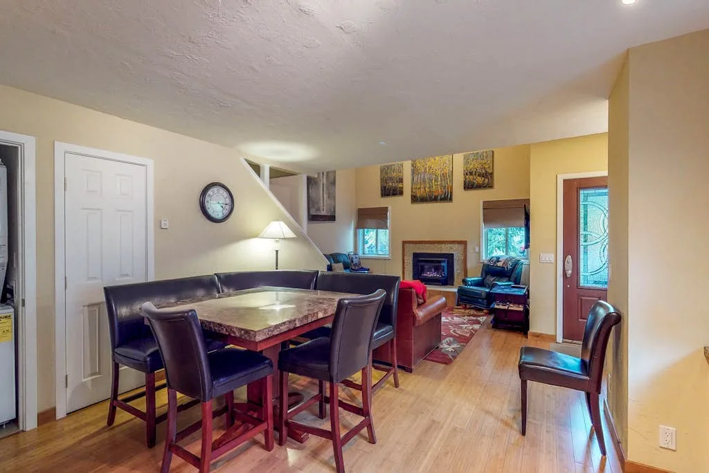 A dining area opens into a living room with seating and a fireplace.