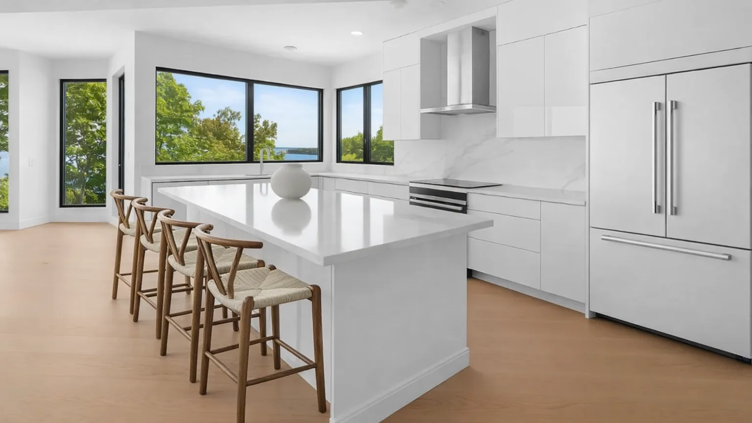 A bright modern kitchen with a large island and windows overlooking trees.