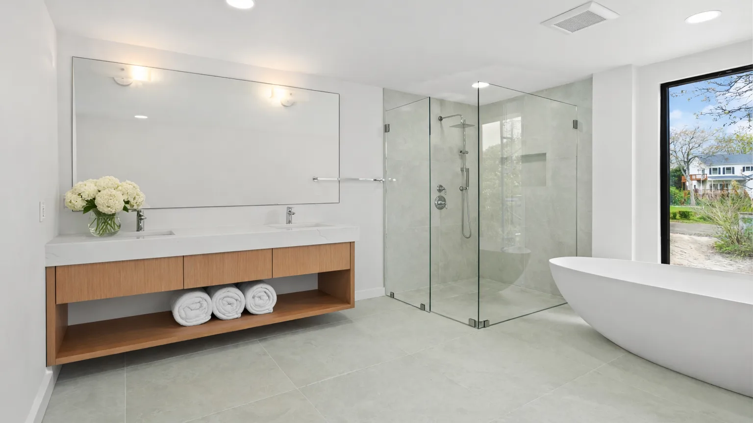 A bright bathroom with a glass shower, a vanity, and a freestanding tub.