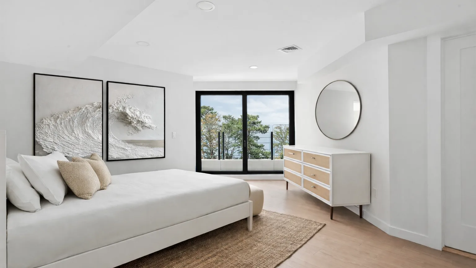 A bright bedroom with a bed, dresser, and large windows.