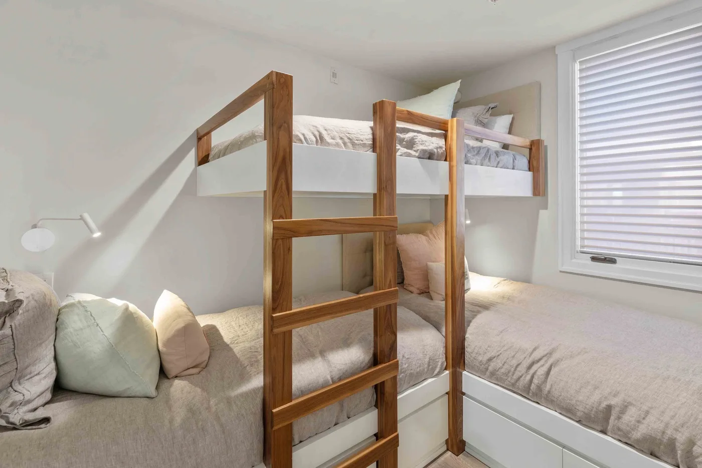 Un dormitorio con una litera de madera sobre una cama inferior y una ventana.