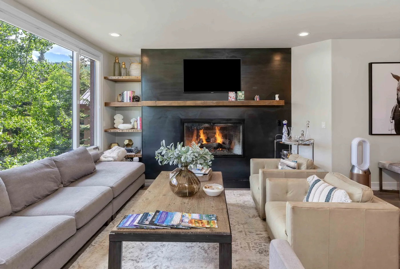 Sala de estar con asientos dispuestos alrededor de una chimenea y un televisor.
