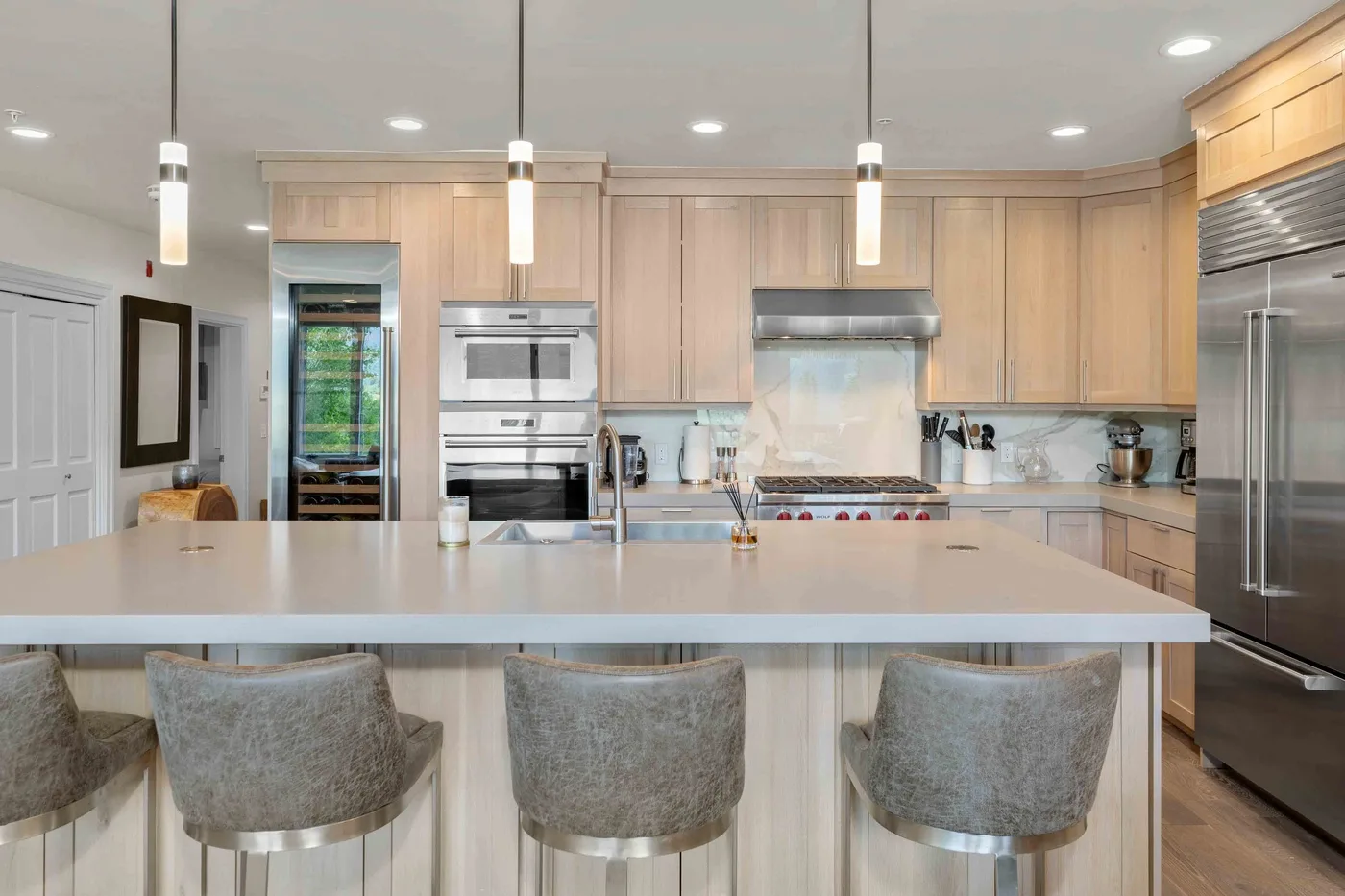Una cocina luminosa con gabinetes de madera clara y una isla grande con asientos.