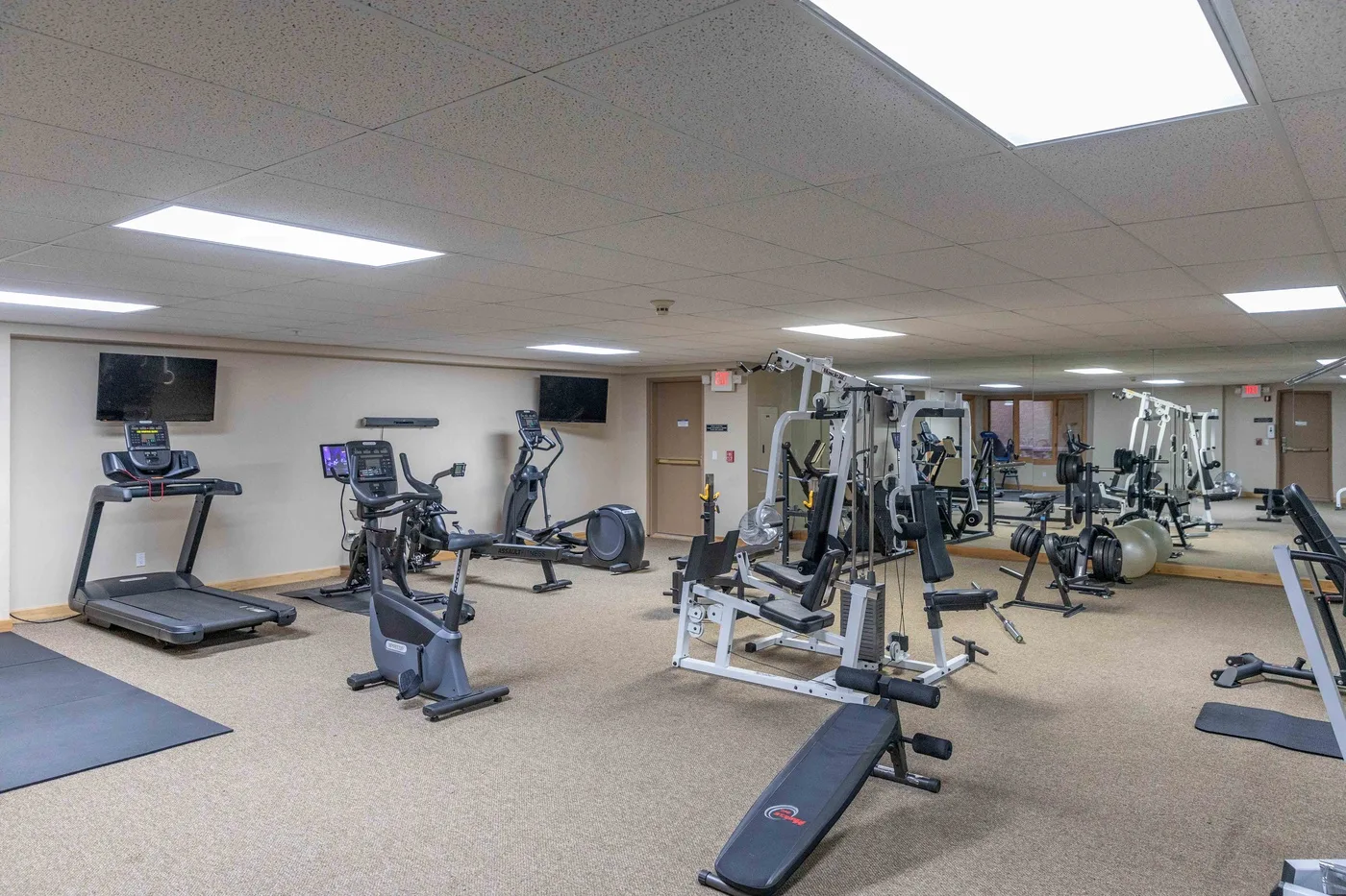 Una sala de ejercicio con cintas de correr, bicicletas estáticas y máquinas de pesas.