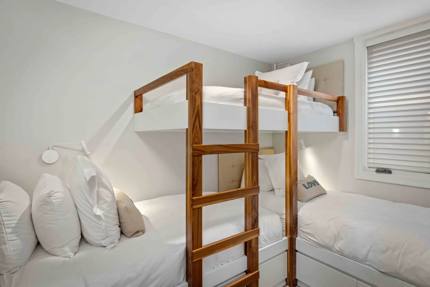 Un dormitorio luminoso con literas y ropa de cama blanca.