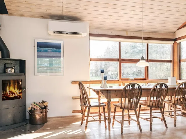 Comedor con una mesa de madera y sillas junto a grandes ventanas.