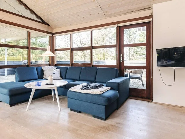 Sala de estar con asientos junto a grandes ventanas y una puerta de vidrio.