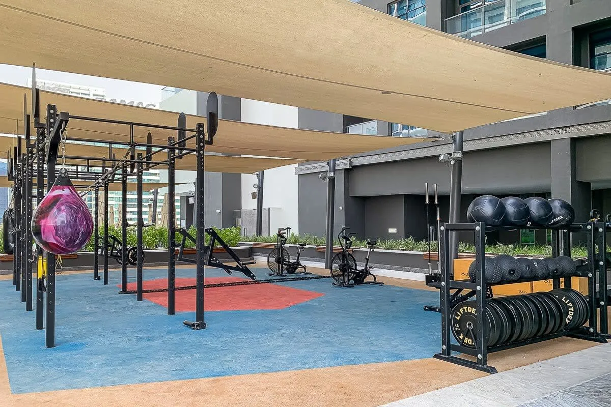 Una zona de ejercicio al aire libre con equipos bajo toldos de sombra.