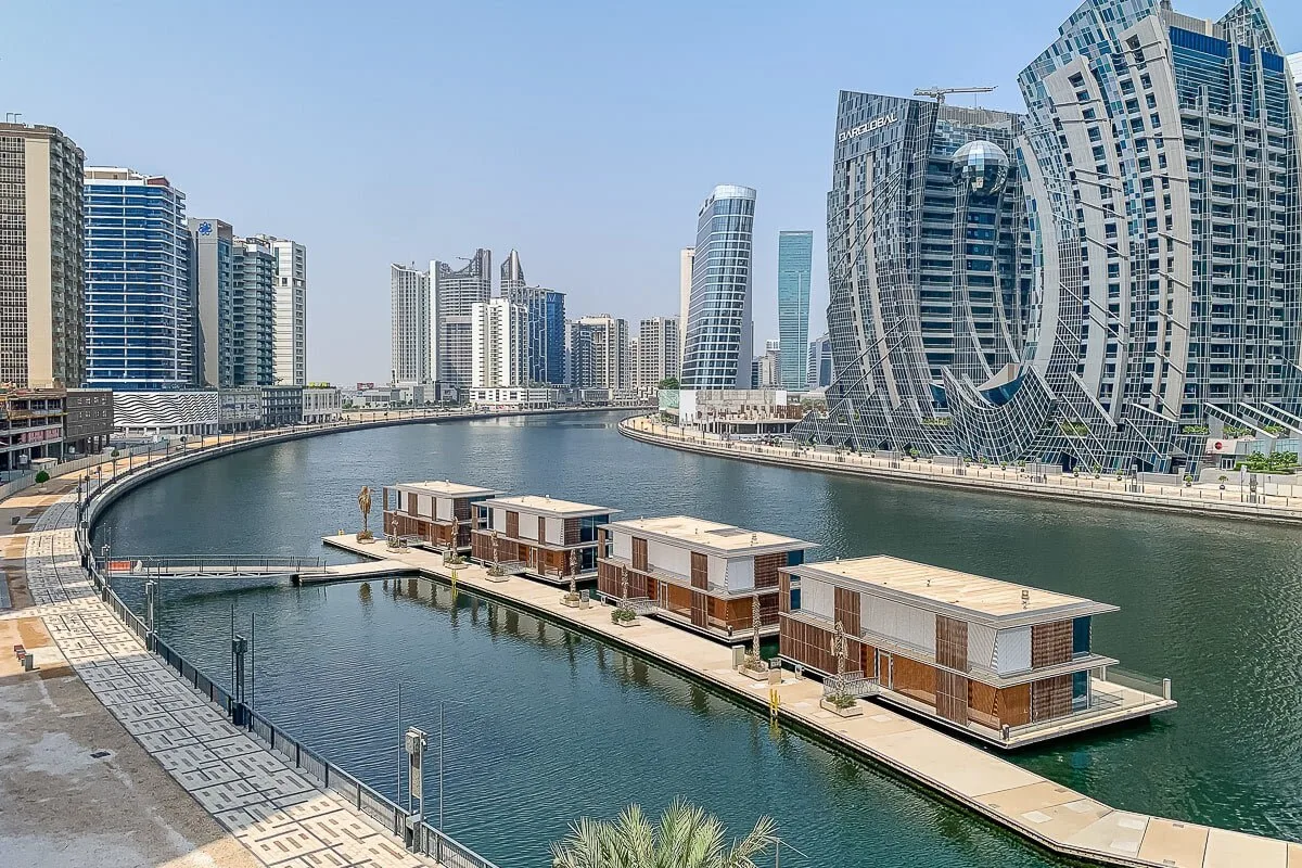 Un canal junto al agua pasa entre edificios modernos altos y estructuras flotantes.