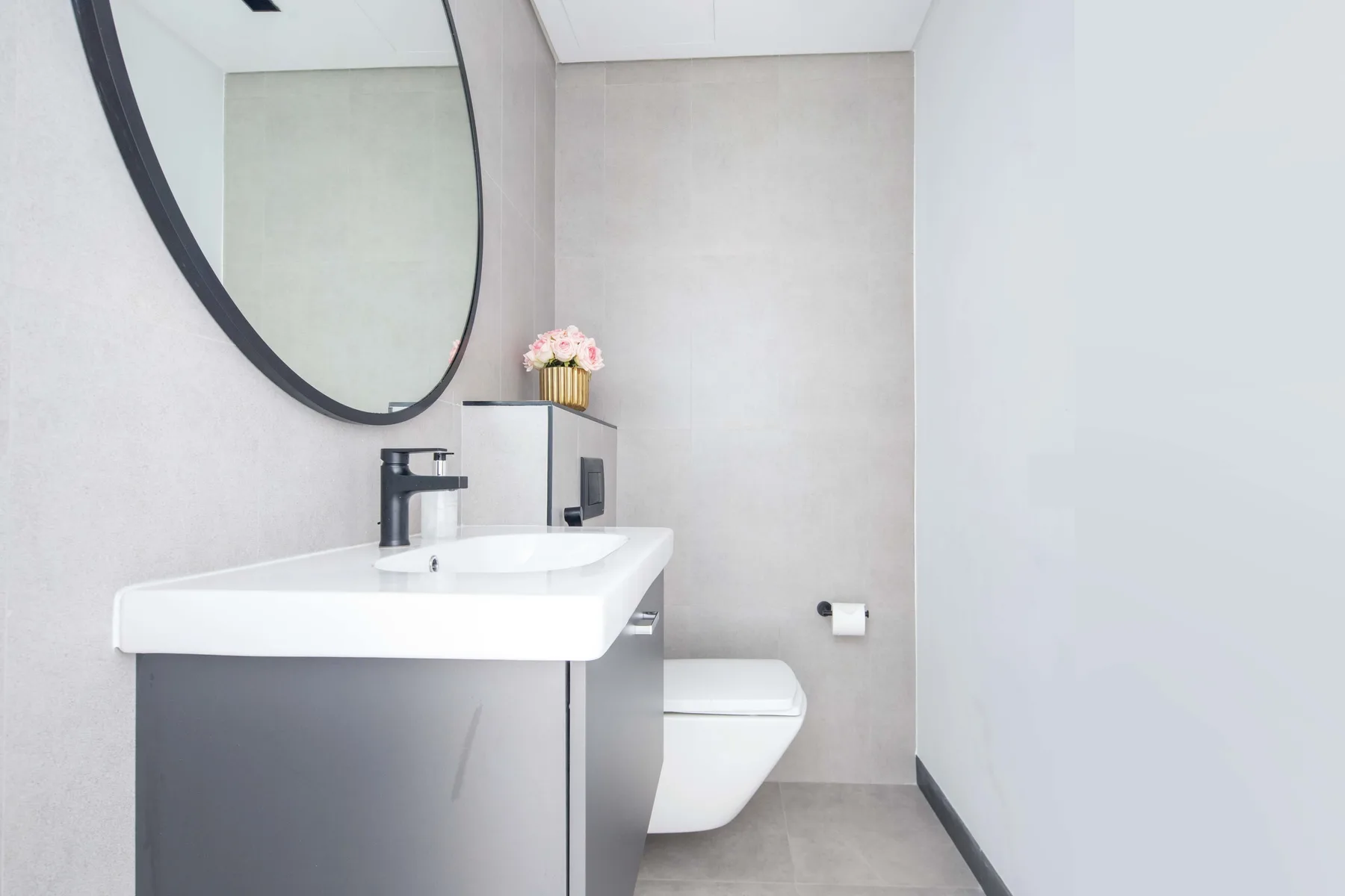 Un baño moderno con lavabo, espejo e inodoro suspendido.