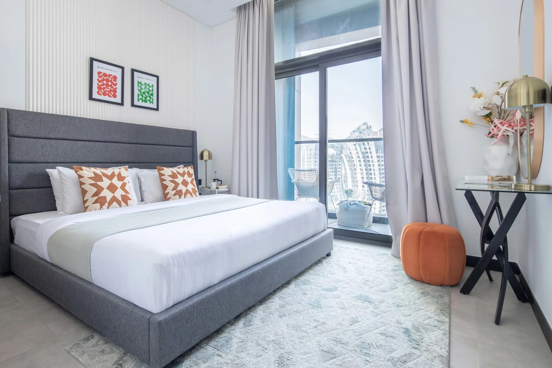 Un dormitorio luminoso con una cama bien hecha junto a una ventana grande.