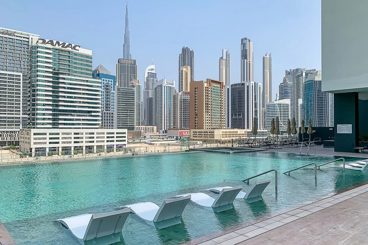 Una piscina en la azotea ofrece vistas de un horizonte urbano de edificios altos.