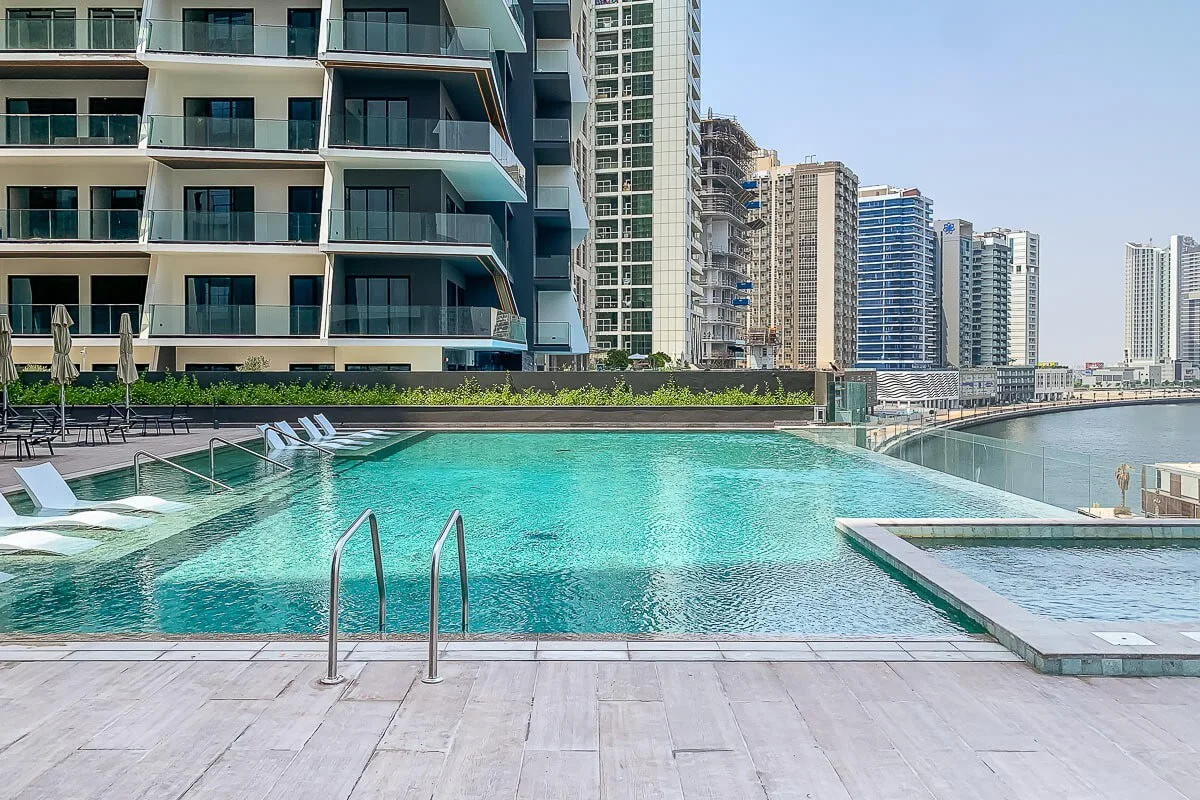Una piscina en la azotea está junto a edificios modernos de gran altura y al paseo marítimo.
