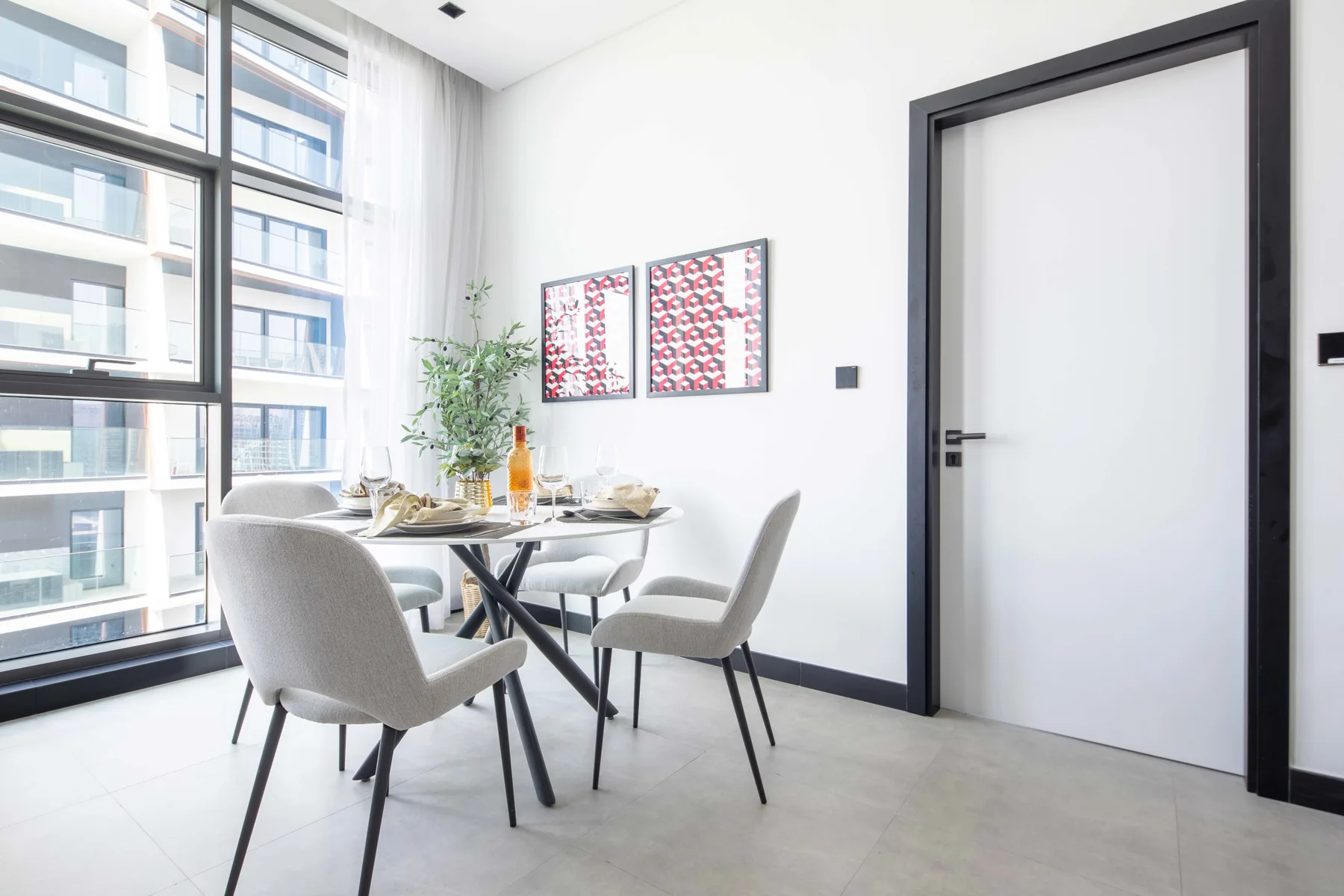 Un comedor luminoso con una mesa y sillas junto a grandes ventanas.