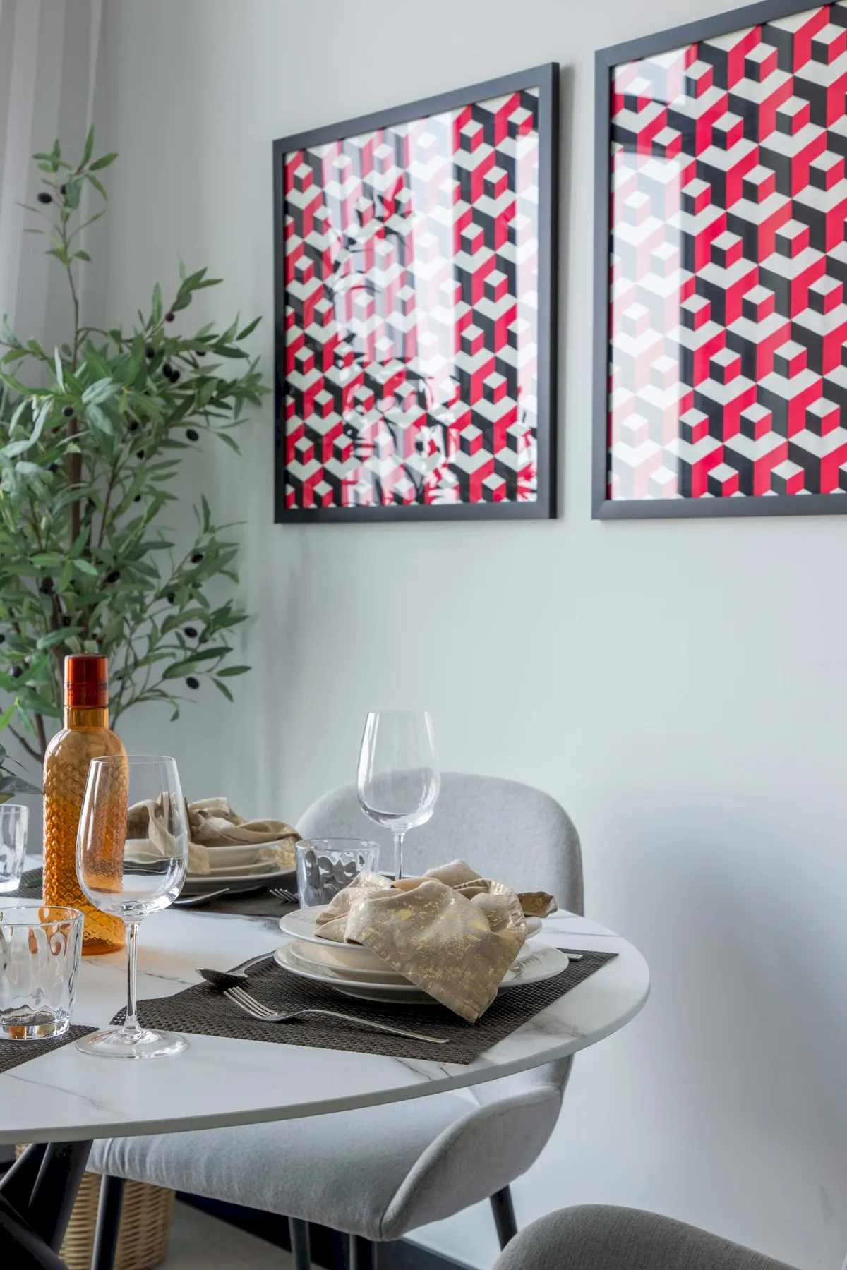 Un comedor con la mesa puesta bajo arte geométrico colorido en la pared.