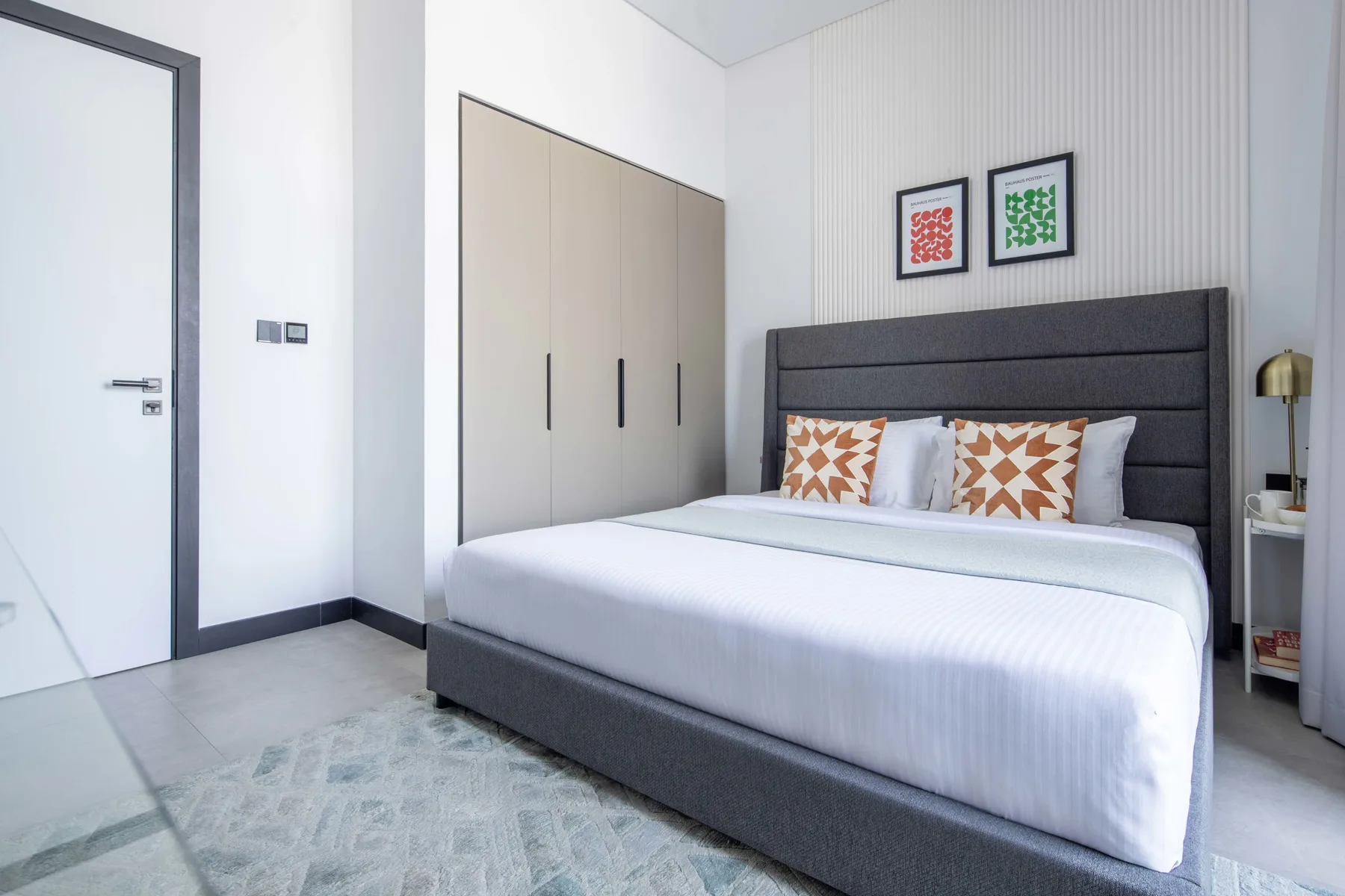 Un dormitorio moderno con una cama grande, cojines estampados y un armario.
