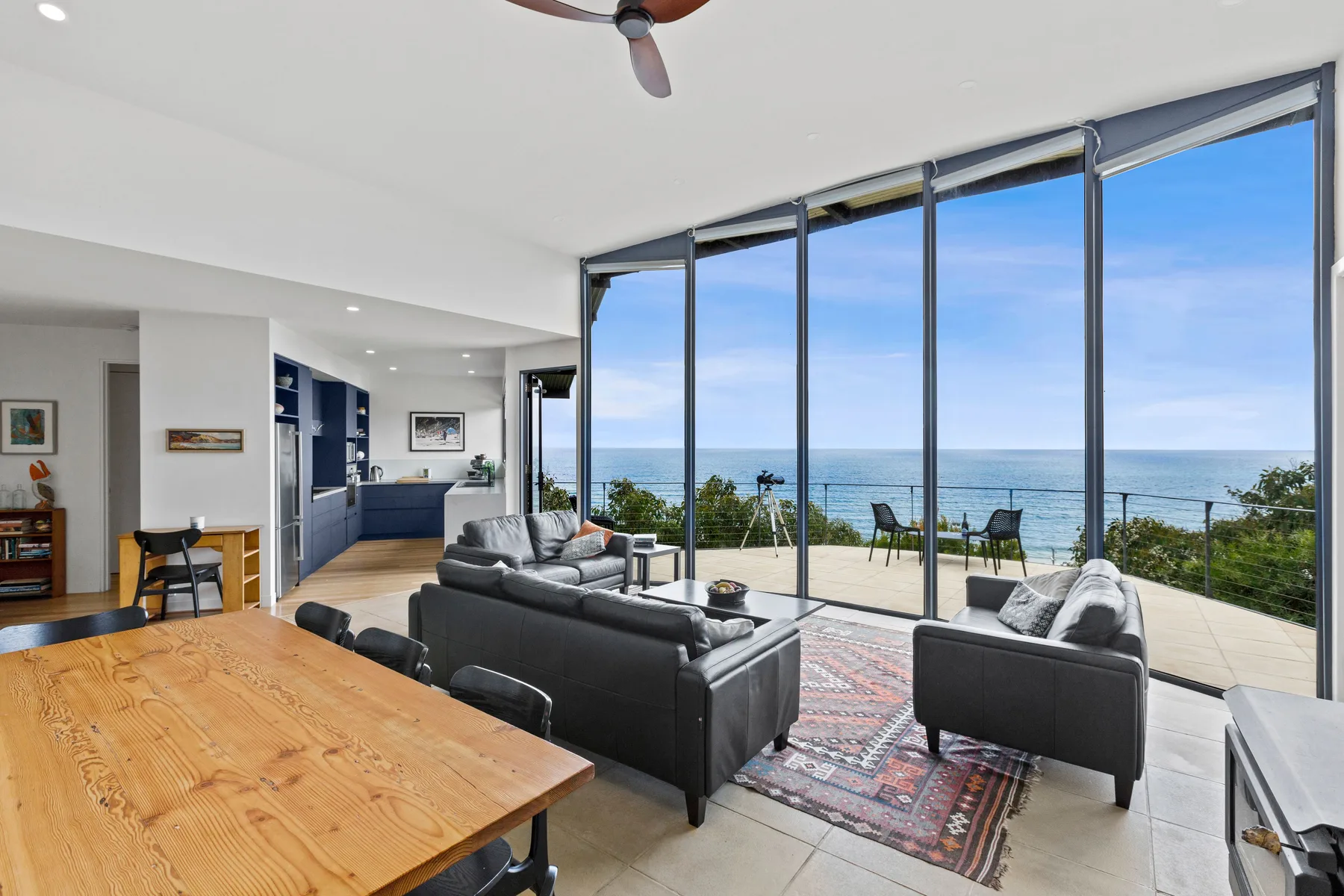 A bright living and dining area opens onto a patio with a view of the ocean.