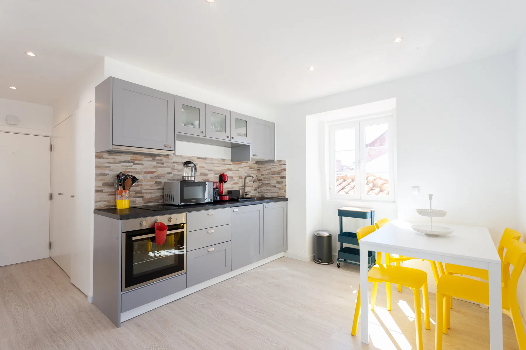 Una cocina luminosa con armarios grises, una encimera y una mesa de comedor.