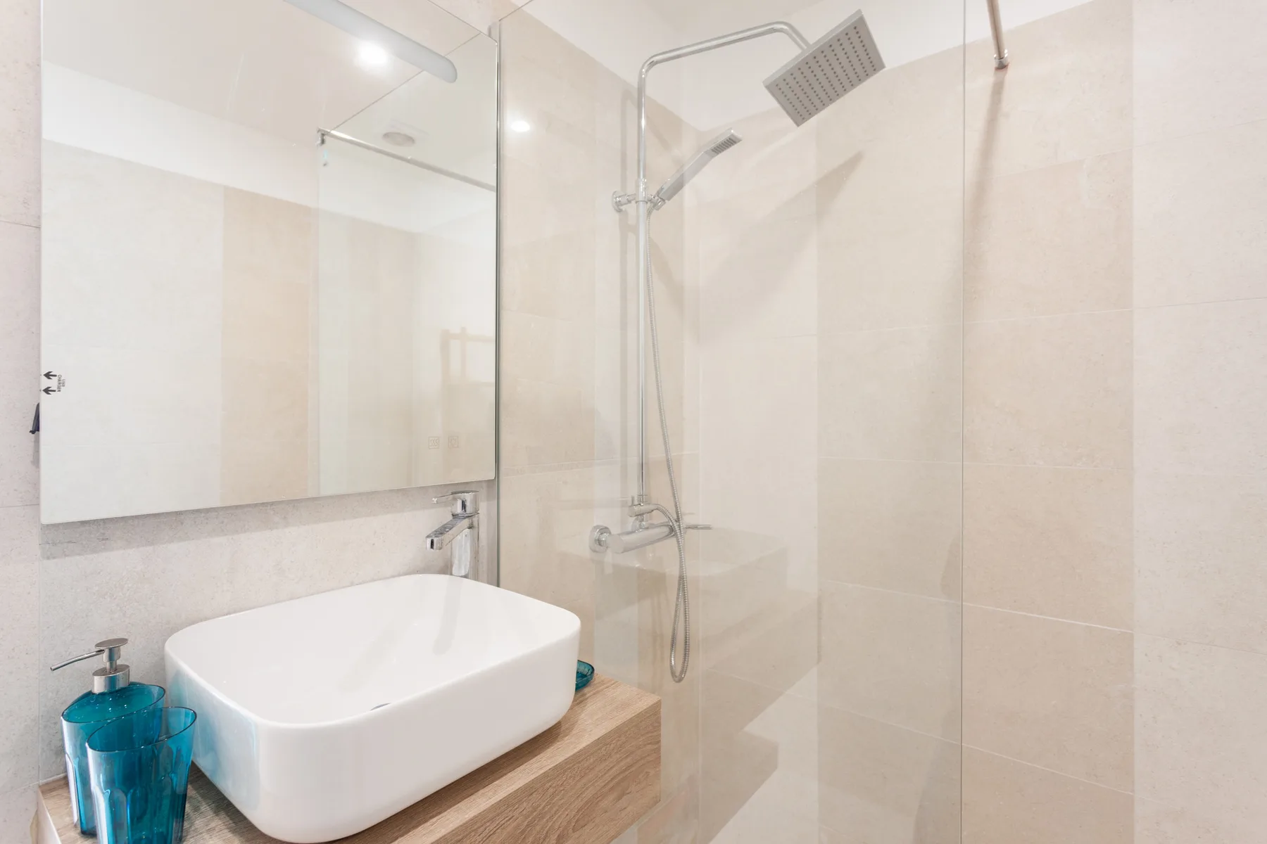Un baño con un lavabo blanco y una ducha con mampara de vidrio.