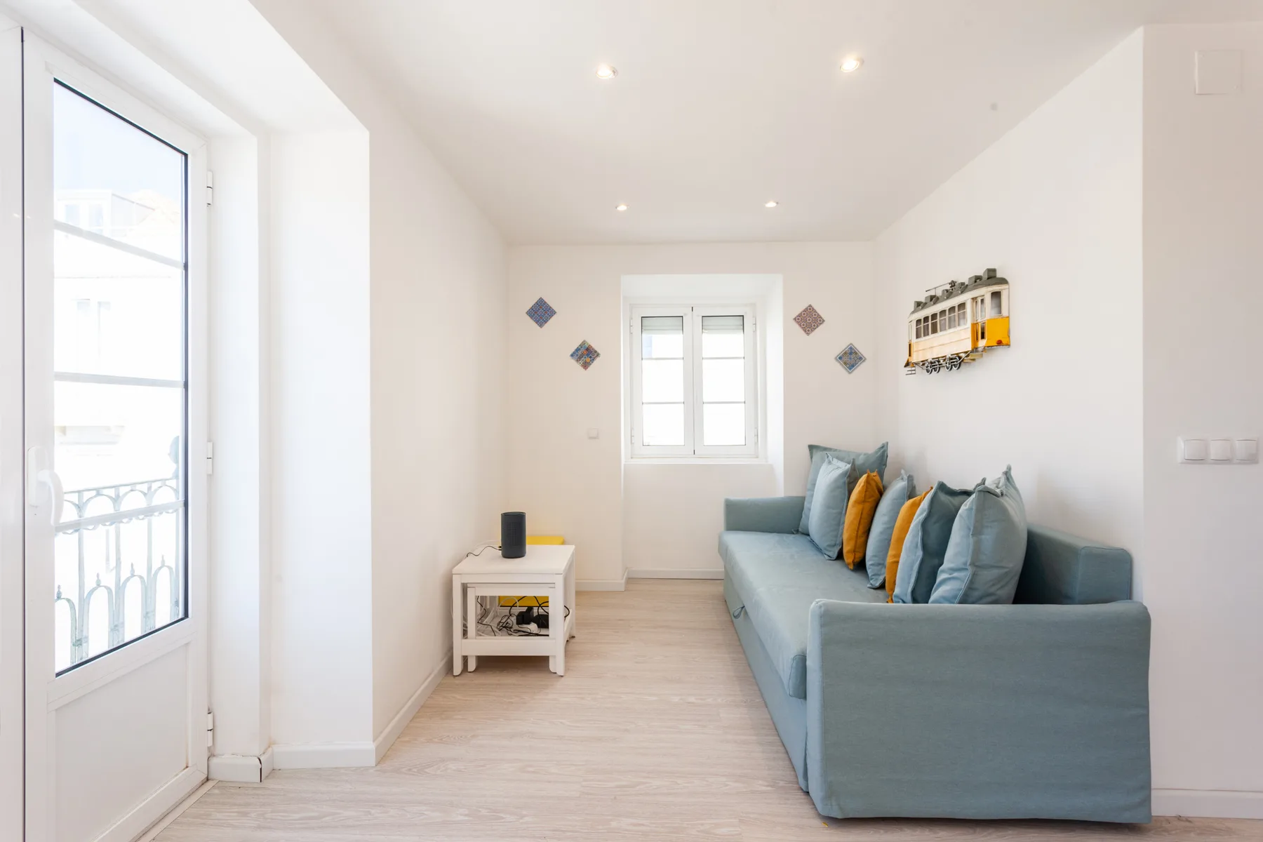 Una sala de estar luminosa con un sofá azul y una ventana pequeña.