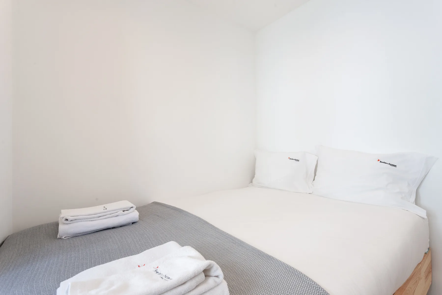 Un dormitorio con una cama cubierta de sábanas blancas y toallas dobladas.