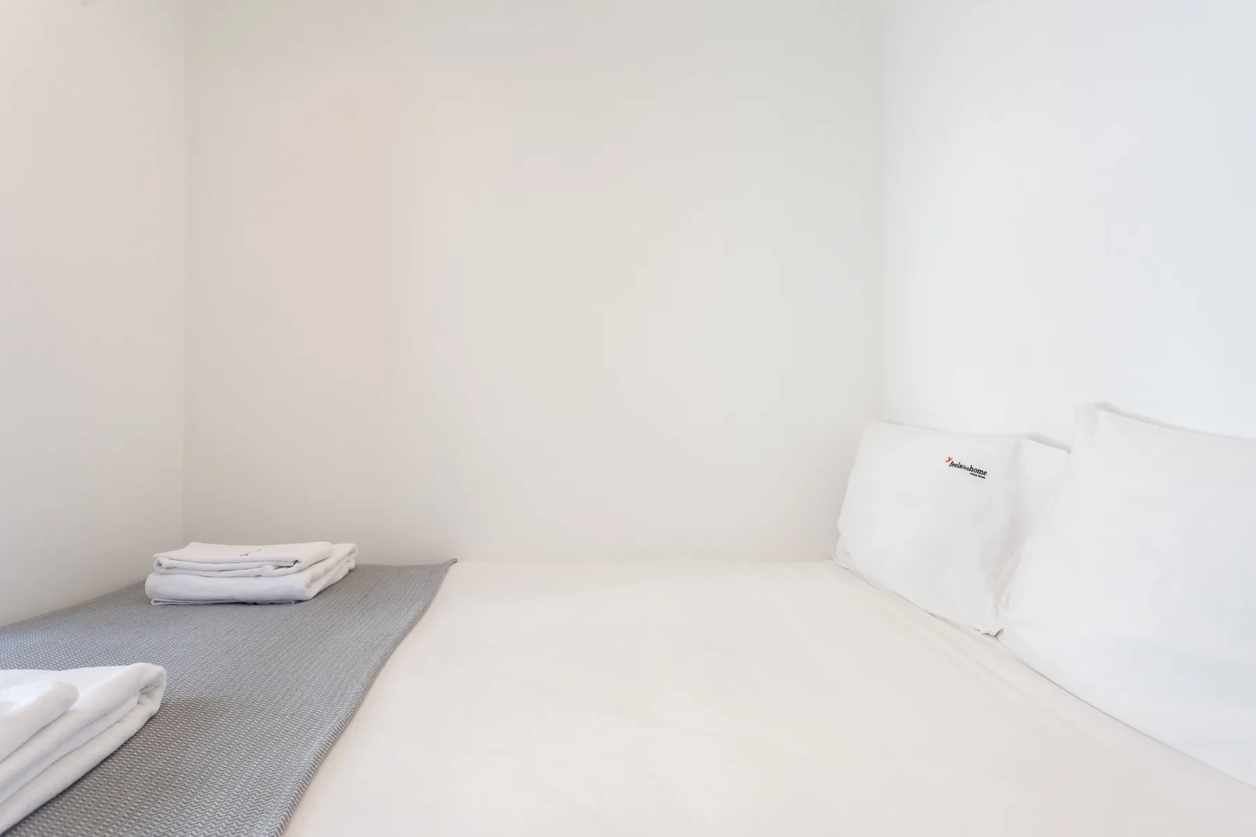 Una cama con ropa de cama blanca y toallas dobladas.